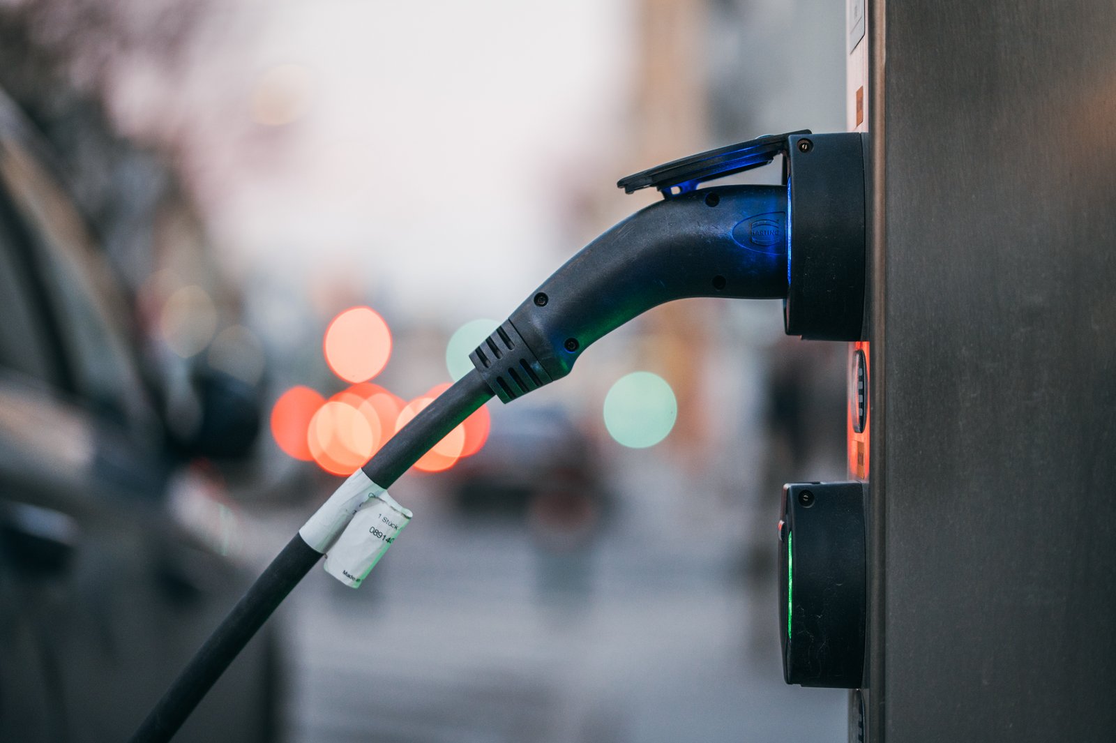 Electric car plugged into a public charging station, cable in focus